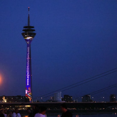 Der Düsseldorfer Fernsehturm und das Rheinufer in der Abenddämmerung.