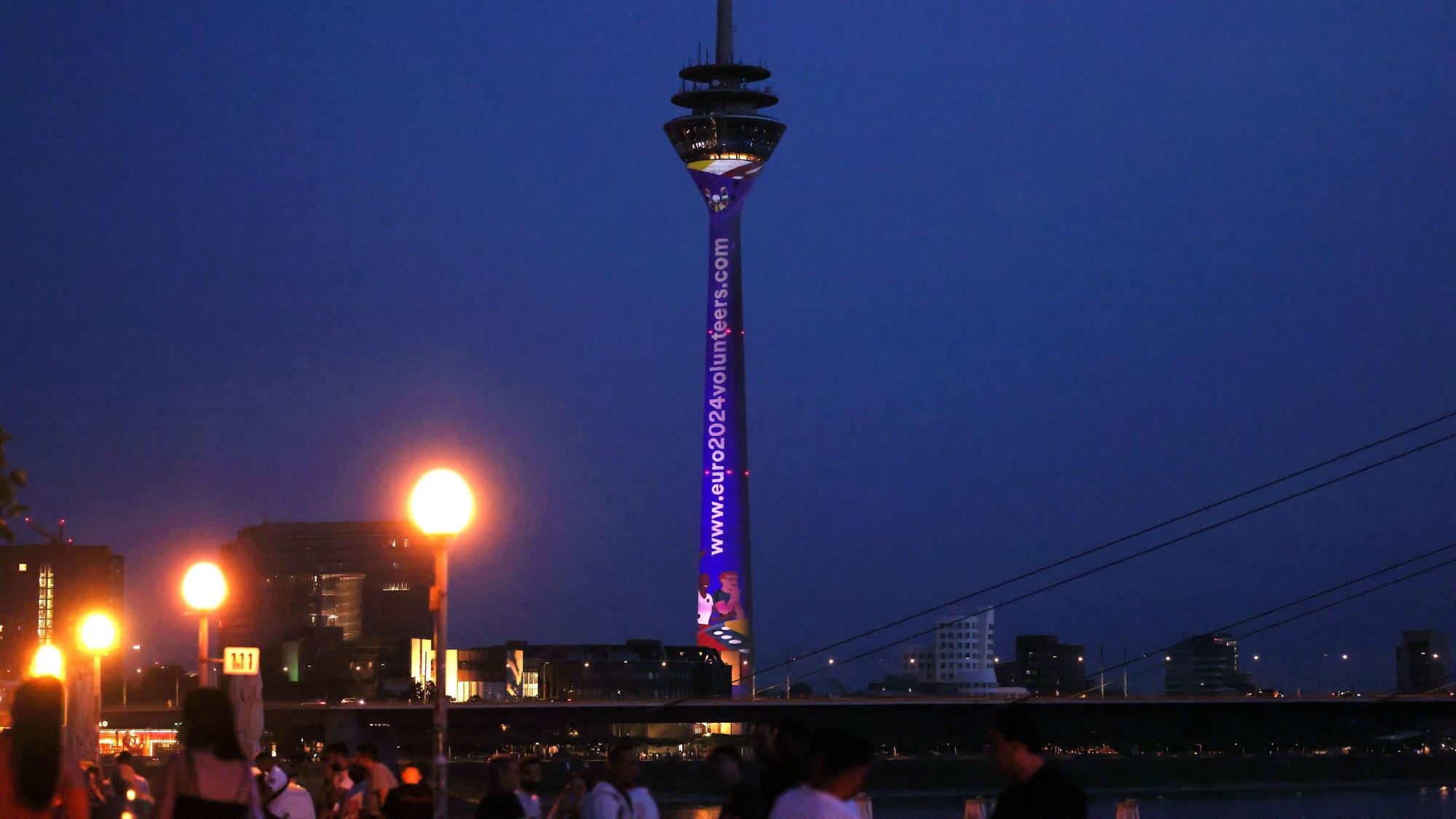 Der Düsseldorfer Fernsehturm und das Rheinufer in der Abenddämmerung.