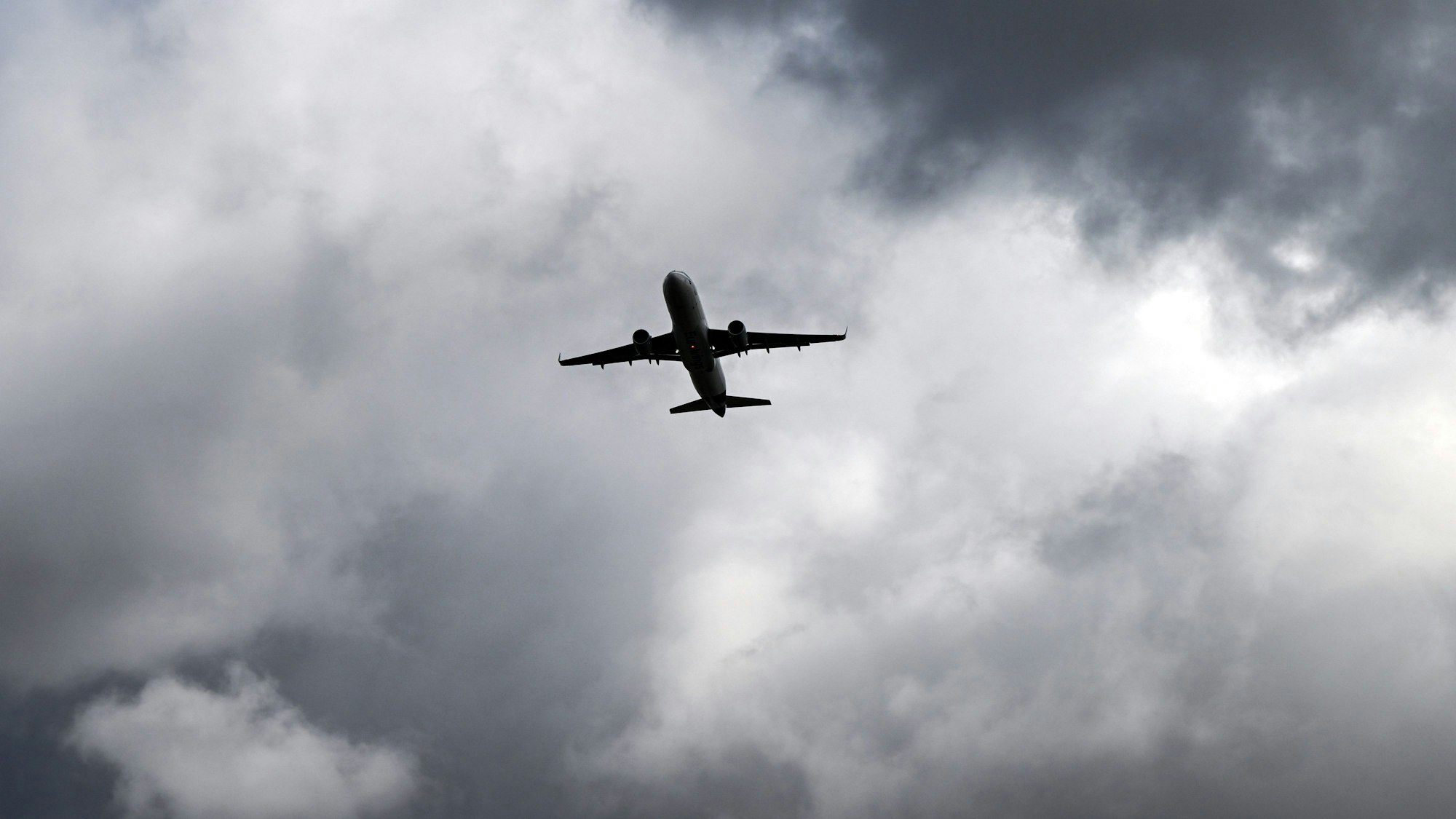 Über einem Flugzeug, das vom Flughafern Düsseldorf startet, türmen sich dunkle Wolken. (Archivbild)