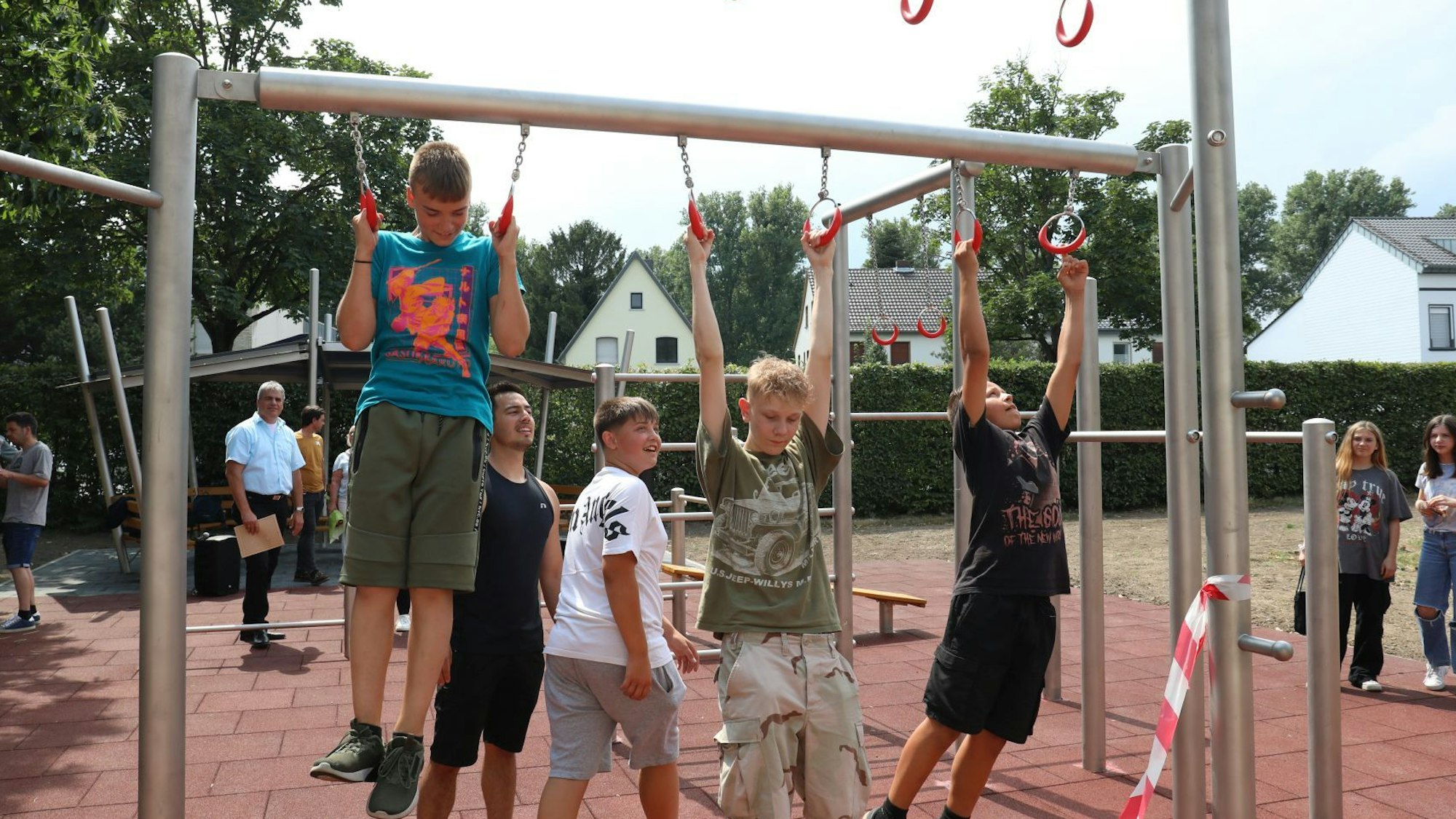 Jugendliche trainieren an den Ringen eines Sportgerätes.