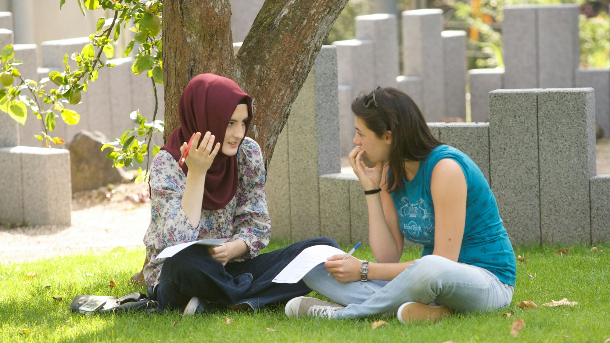 Zwei junge Frauen sitzen auf einer Wiese.
