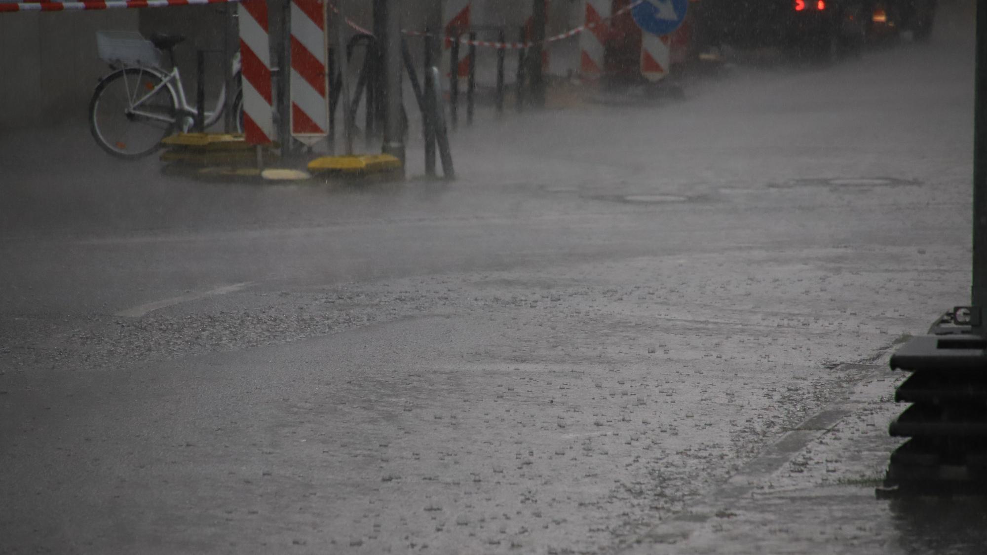 Ein Starkregen setzt eine Straße in Rhein-Sieg unter Wasser. Die Fahrbahn selbst ist kaum noch zu erkennen.