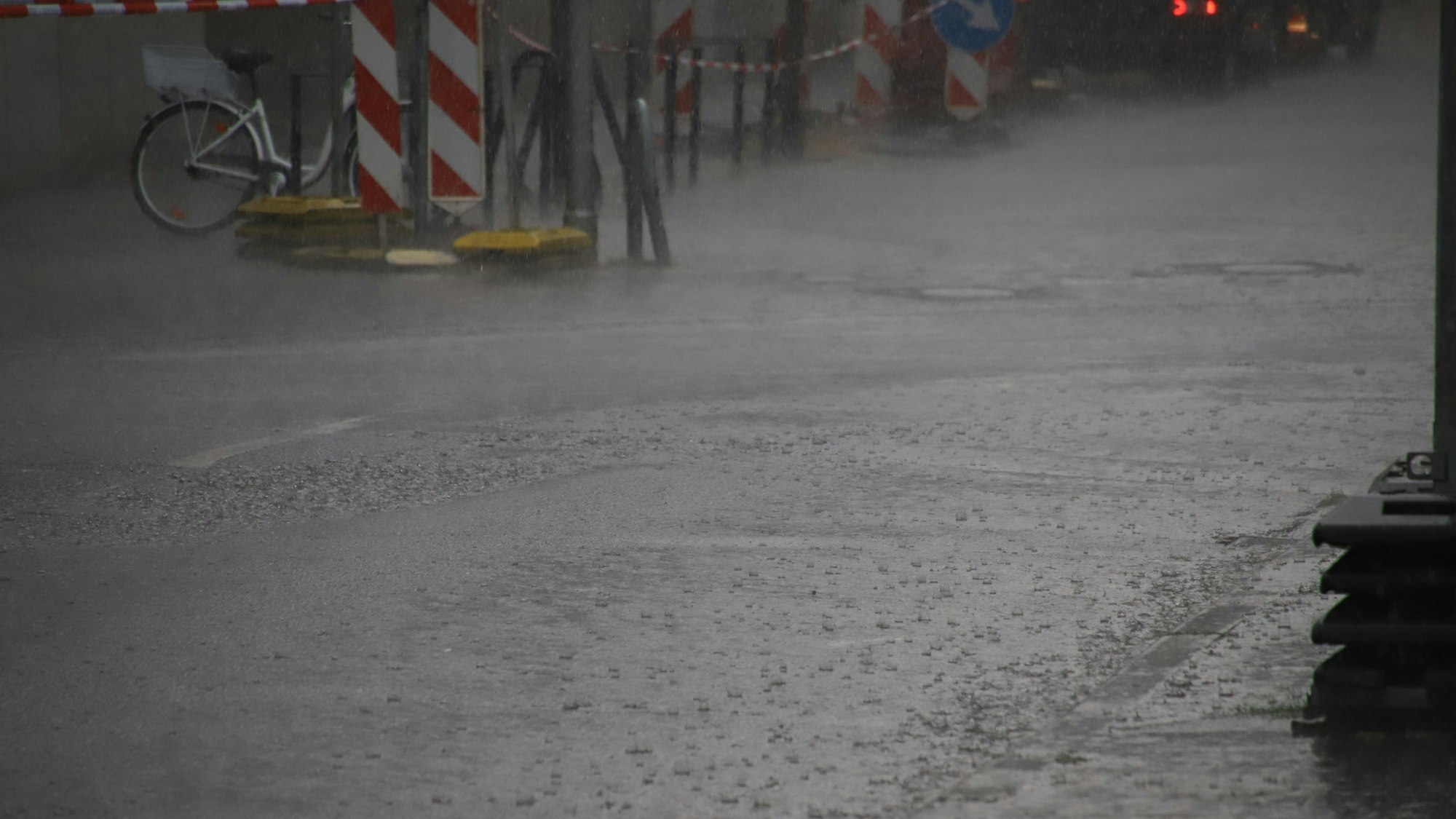 Ein Starkregen setzt eine Straße in Rhein-Sieg unter Wasser. Die Fahrbahn selbst ist kaum noch zu erkennen.