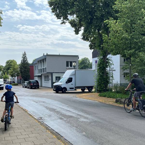 Kind fährt auf Gehweg, Transporter auf der Straße