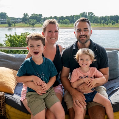 Verena und Caroll Zosel mit Milo (links) und Jarno sitzen auf ihrem Balkon in Mülheim. Im Hintergrund ist der Rhein zu sehen.