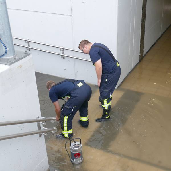 Zwei Feuerwehrleute stehen in der vollgelaufenen Unterführung des Bahnhofs in Friedrich-Wilhelms-Hütte.