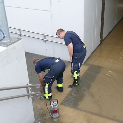 Zwei Feuerwehrleute stehen in der vollgelaufenen Unterführung des Bahnhofs in Friedrich-Wilhelms-Hütte.