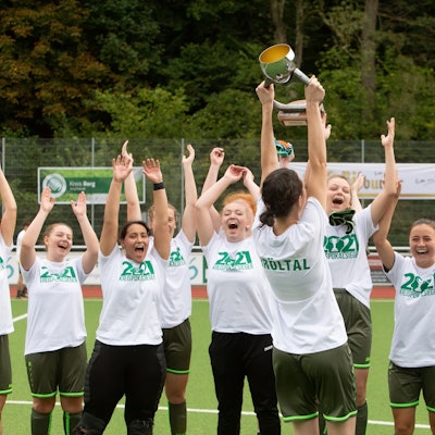 Jubelnde Fußballerinnen recken einen Pokal in die Höhe.