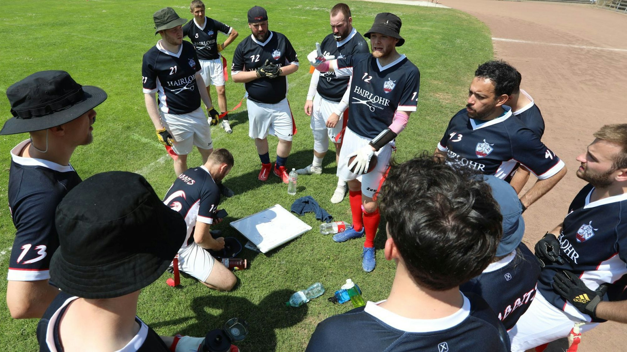Spieler der Mannschaft stehen am Spielfeldrand zusammen und besprechen die Spielstrategie.