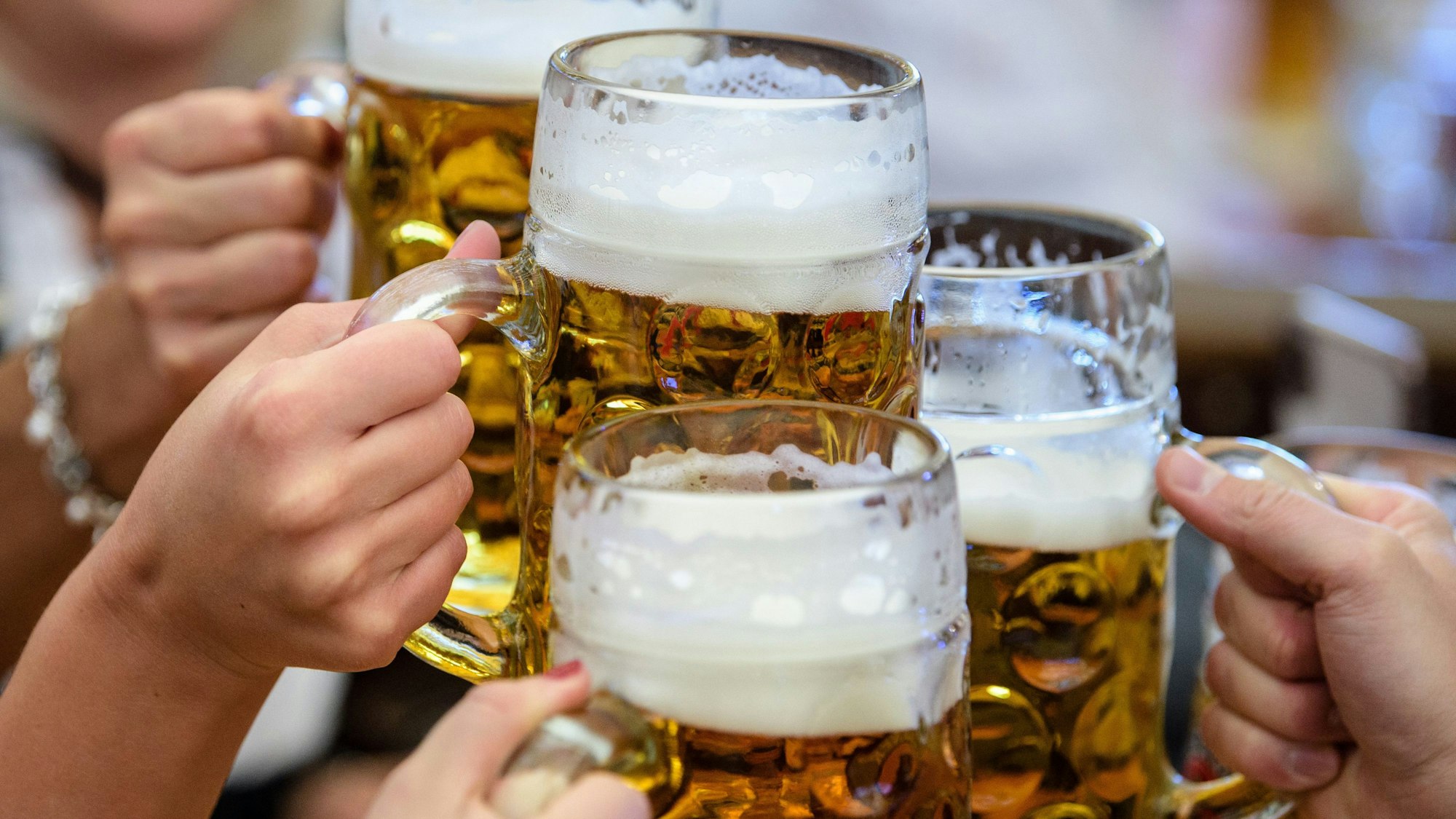 Besucherinnen prosten sich beim Auftakt zum Oktoberfest im Paulaner-Festzelt mit ihrer ersten Maß Bier zu.
