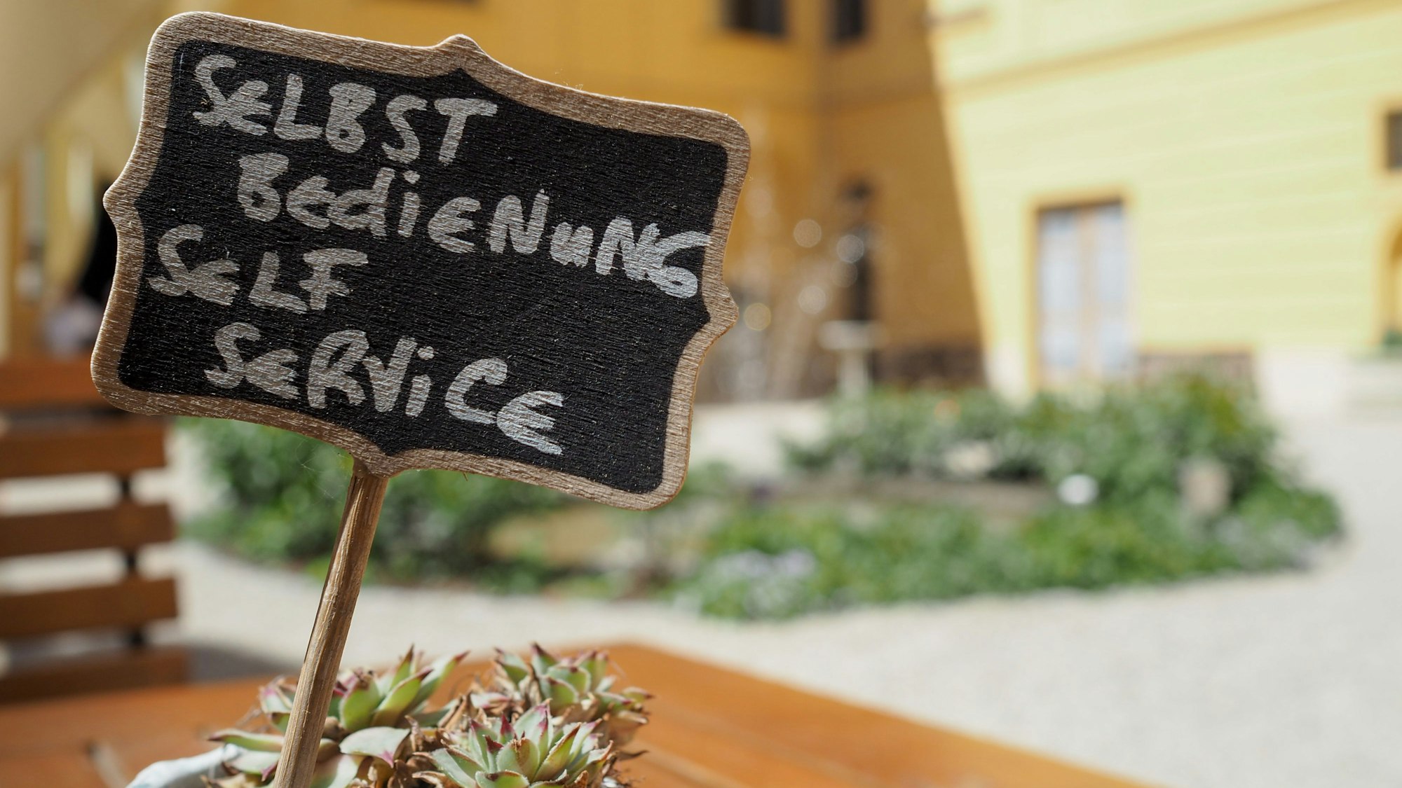 Ein Schild mit der Aufschrift Selbstbedienung in Deutsch und Englisch.