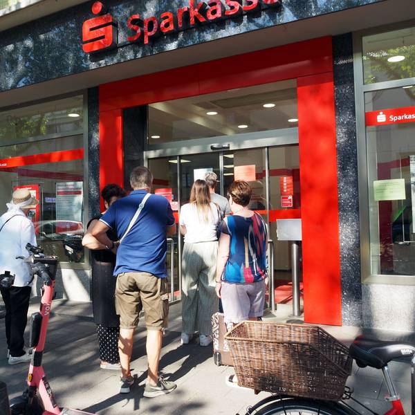 Viele Menschen stehen vor der Sparkasse.