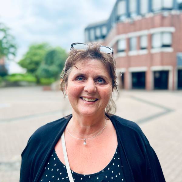 Eine Frau mittleren Alters schaut lächelnd in die Kamera. Die Brille hat sie in ihr dunkles zurückgestecktes Haar hochgeschoben.