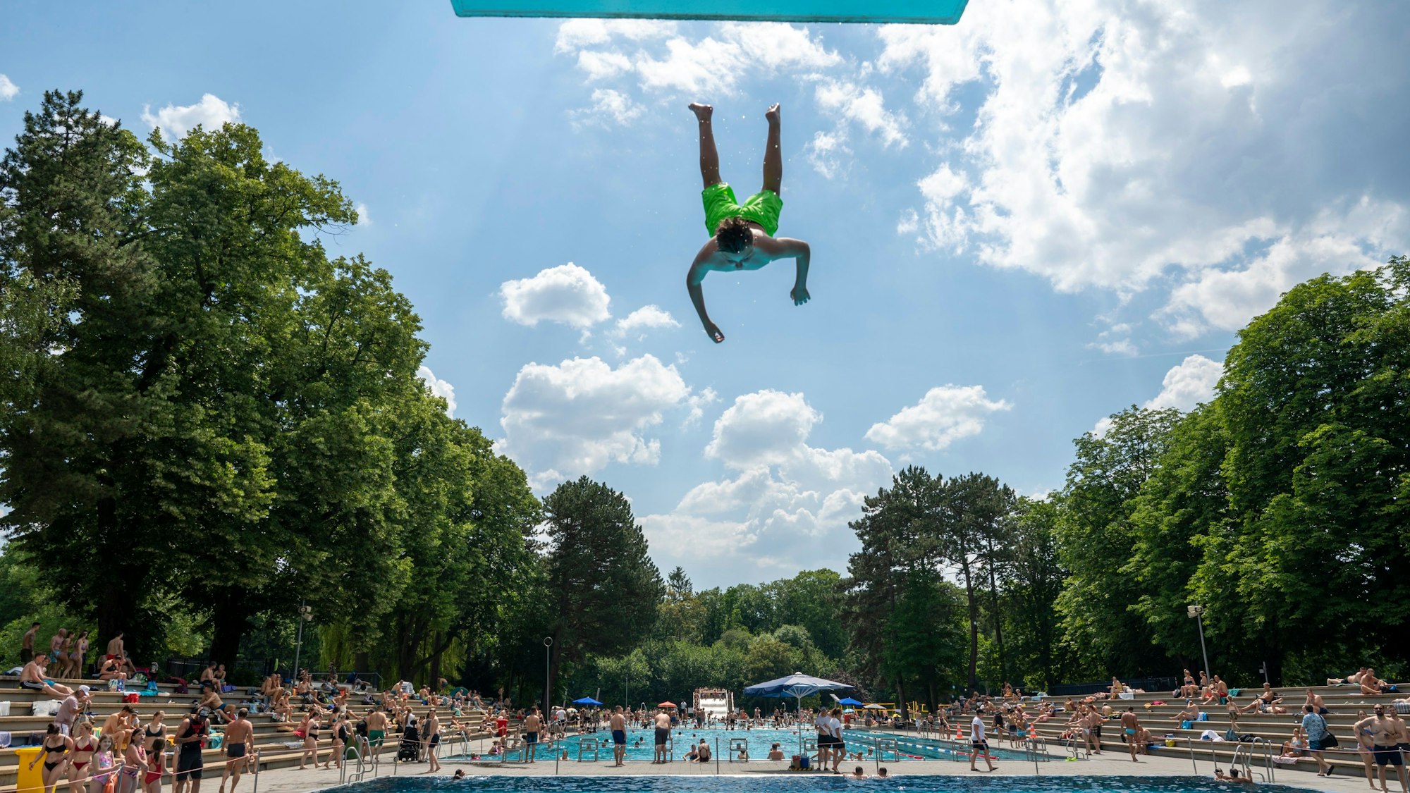 Ein Mann springt kopfüber vom Sprungbrett ins Becken des Kölner Stadionbad.