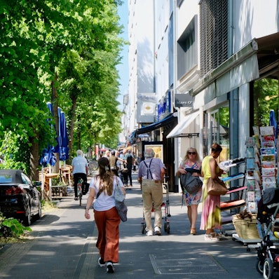 Eine Straße mit parkenden Autos, Rad- und Gehweg ist zu sehen.