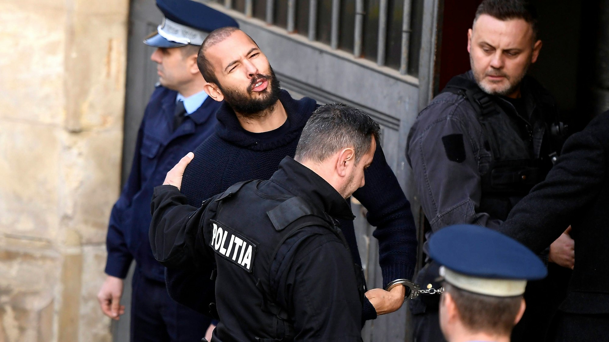 Der frühere Influencer Andrew Tate wird von Polizisten abgeführt. Das rumänische Gericht hat Tates Hausarrest verlängert. (Archivbild)