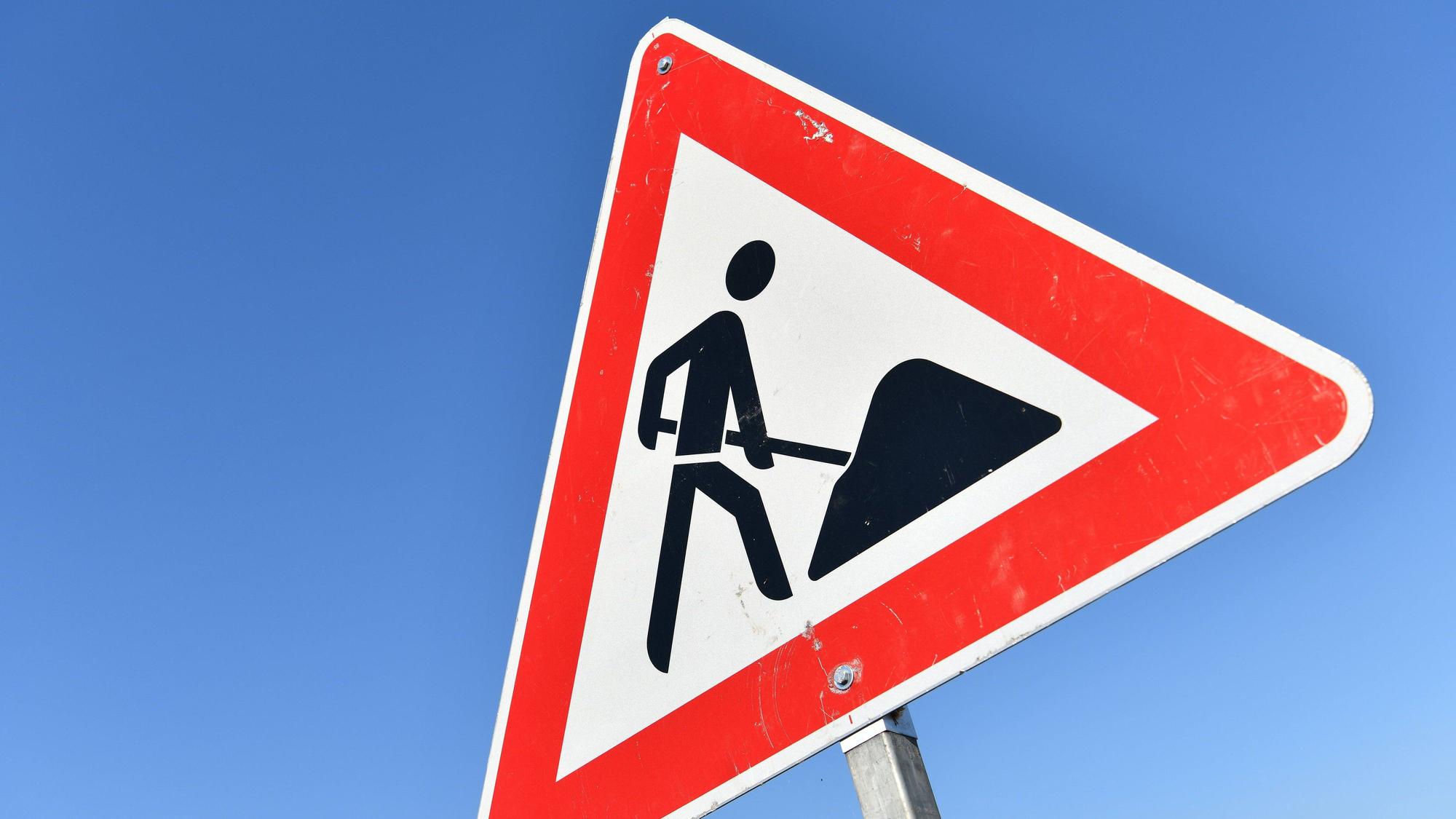Das Foto zeigt das Verkehrszeichen „Achtung Baustelle“ vor blauem Himmel.