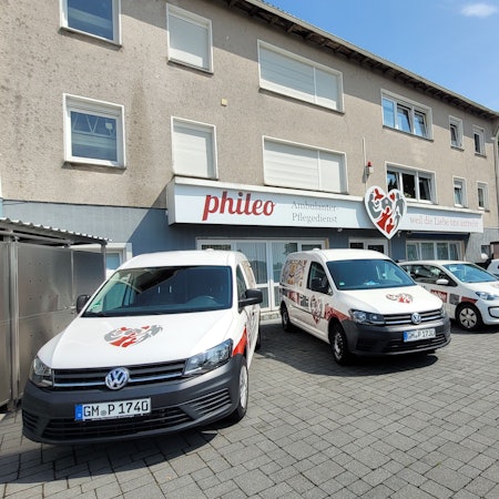 Mehrere VW-Caddys eines Pflegedienstes stehen auf einem Hof nebeneinander.