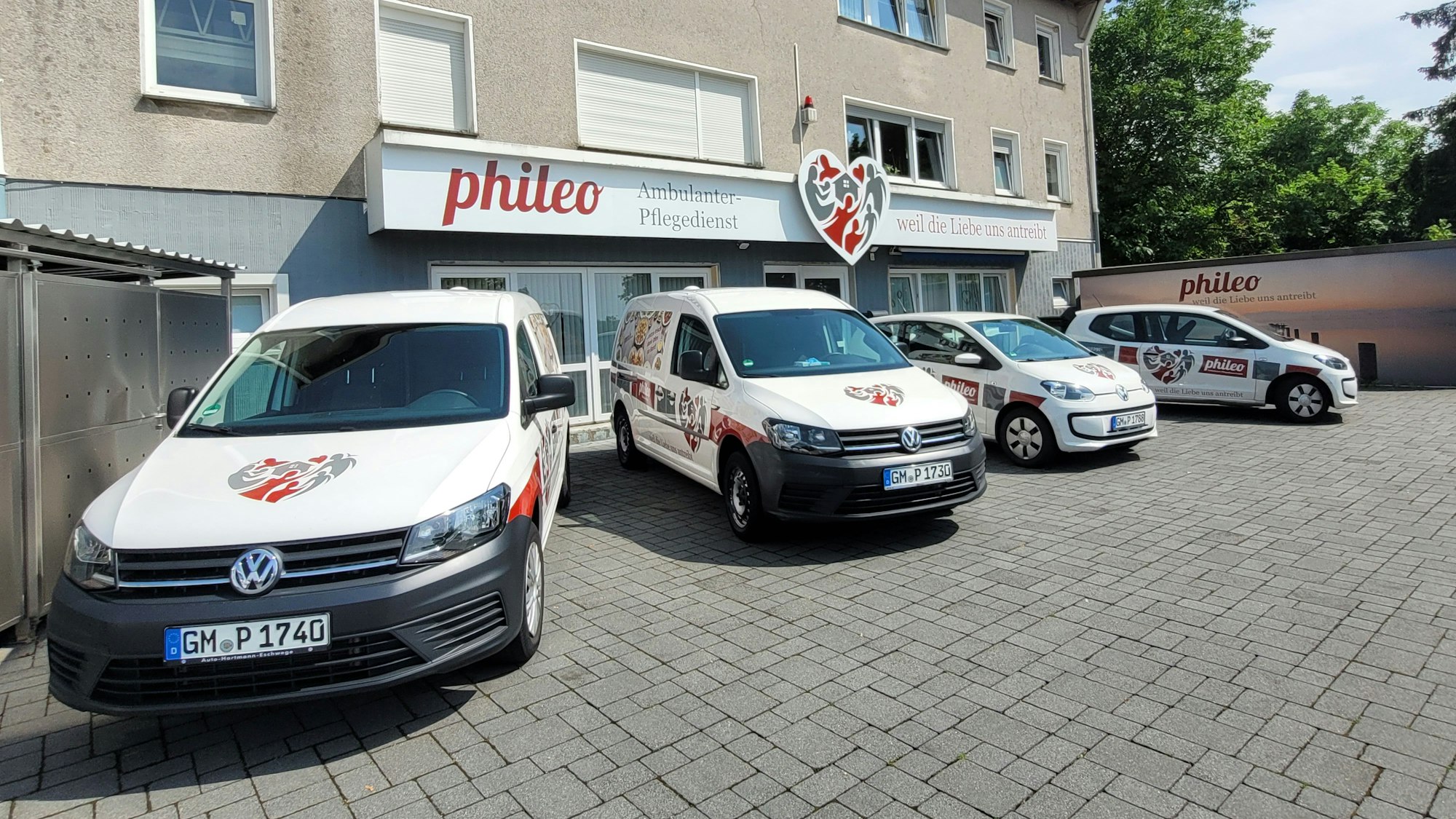 Mehrere VW-Caddys eines Pflegedienstes stehen auf einem Hof nebeneinander.