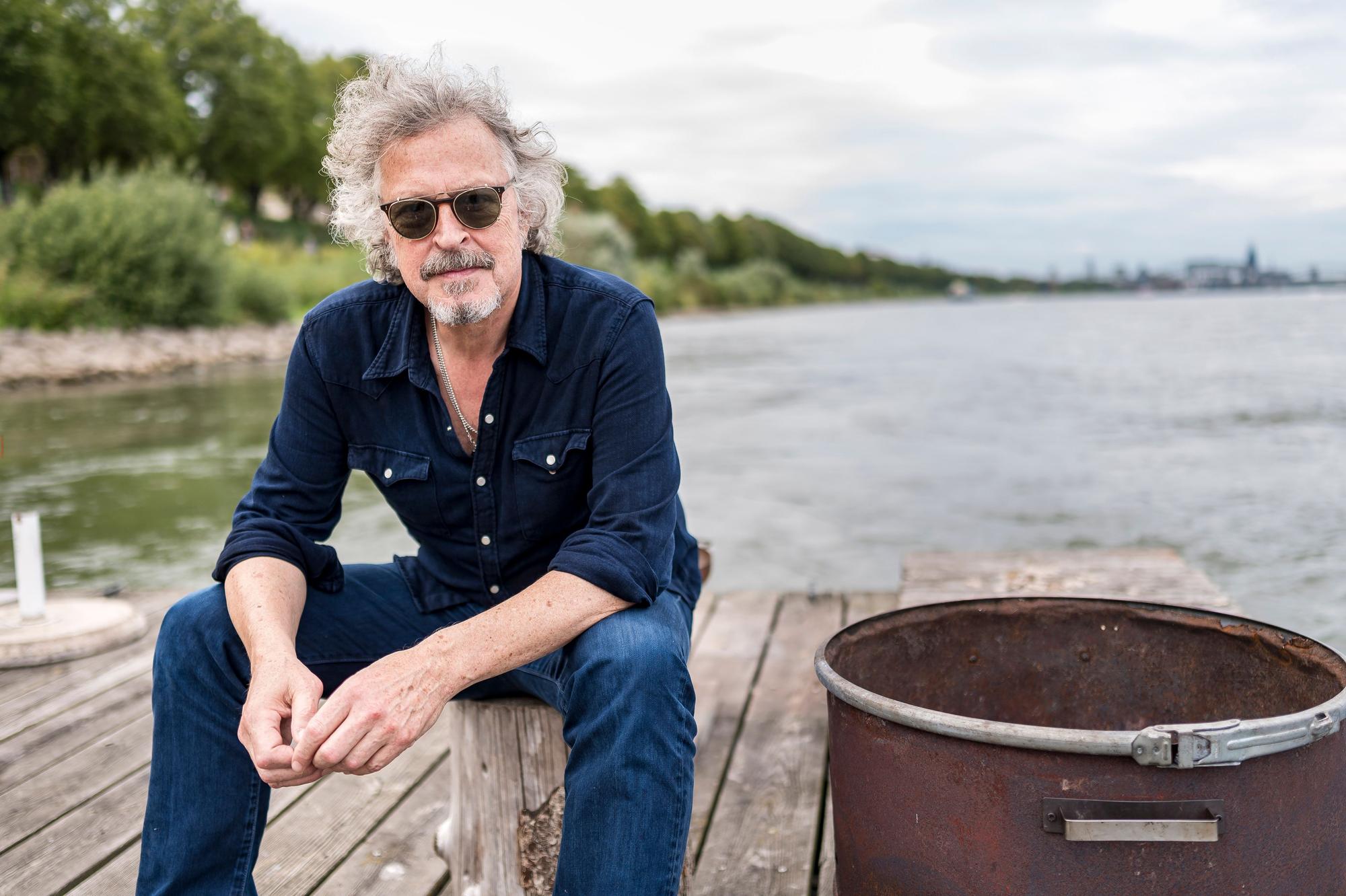 Wolfgang Niedecken sitzt am Rhein.