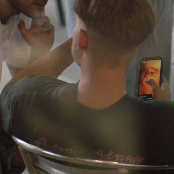 Ein Junge sitzt in einem Stuhl und hält sein Mobiltelefon in der Hand.