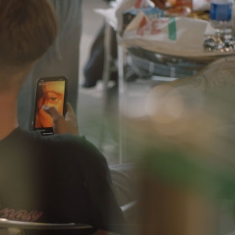 Ein Junge sitzt in einem Stuhl und hält sein Mobiltelefon in der Hand.