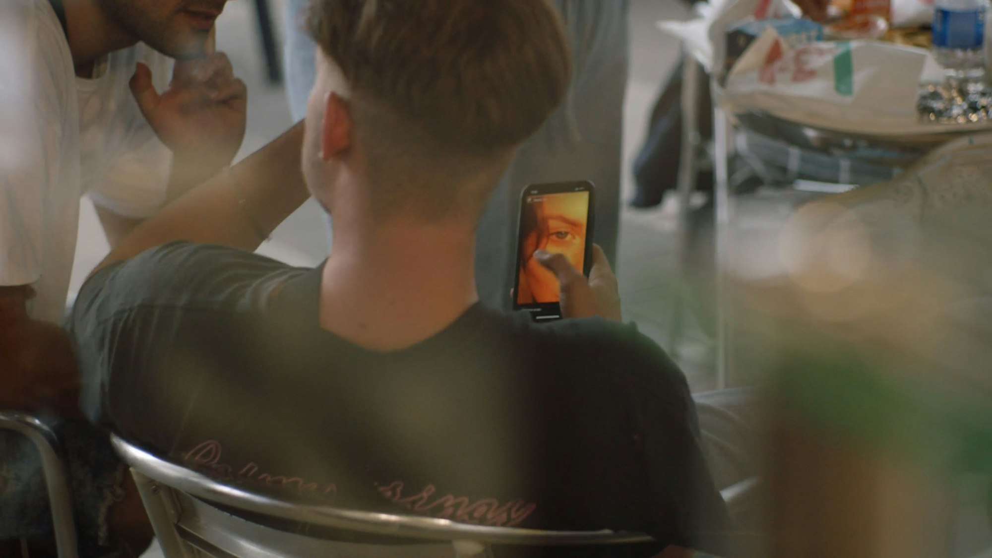 Ein Junge sitzt in einem Stuhl und hält sein Mobiltelefon in der Hand.