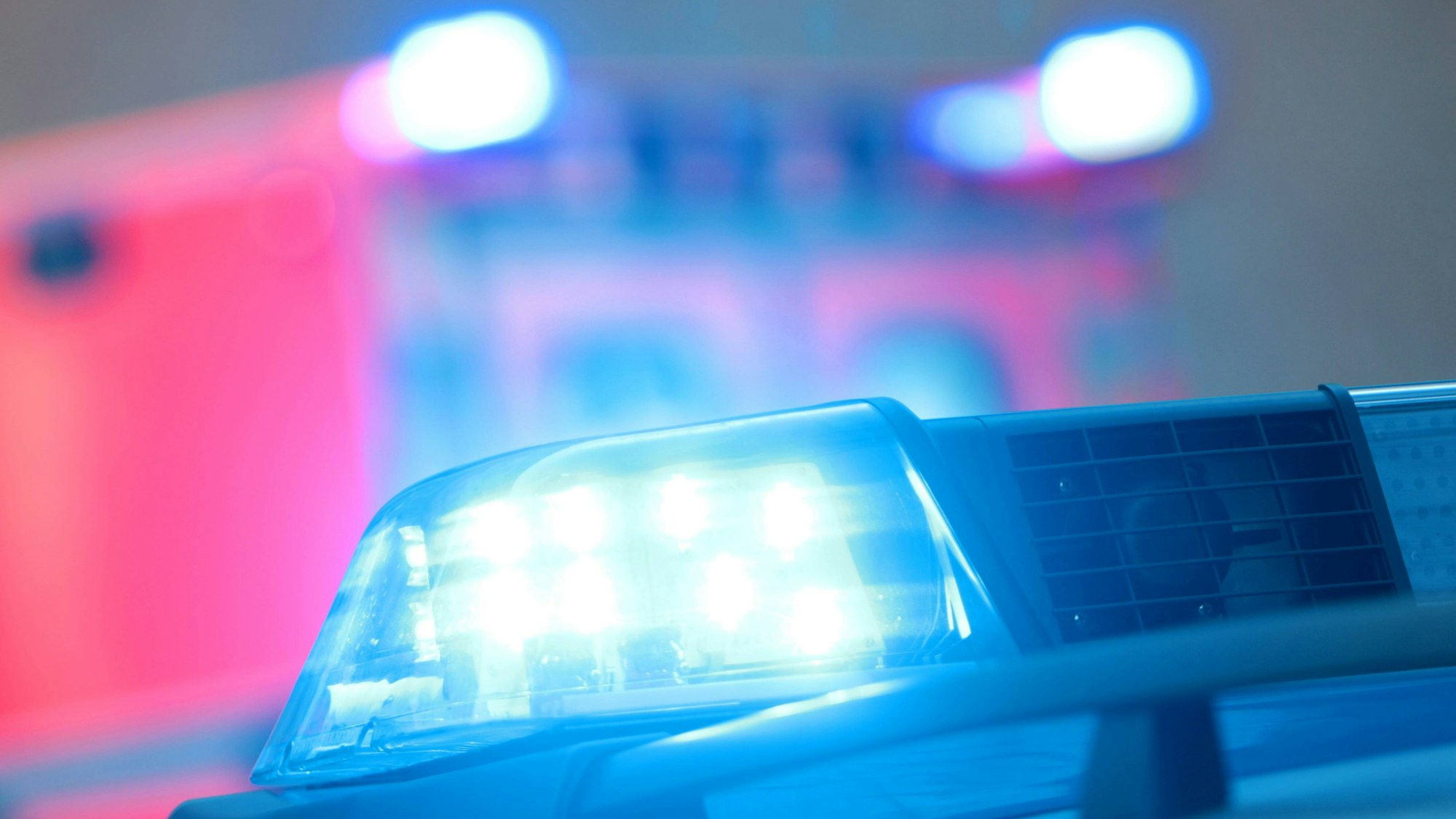 Einsatzwagen der Polizei mit eingeschaltetem Blaulicht und Notarzt Rettungswagen bei einem Einsatz.