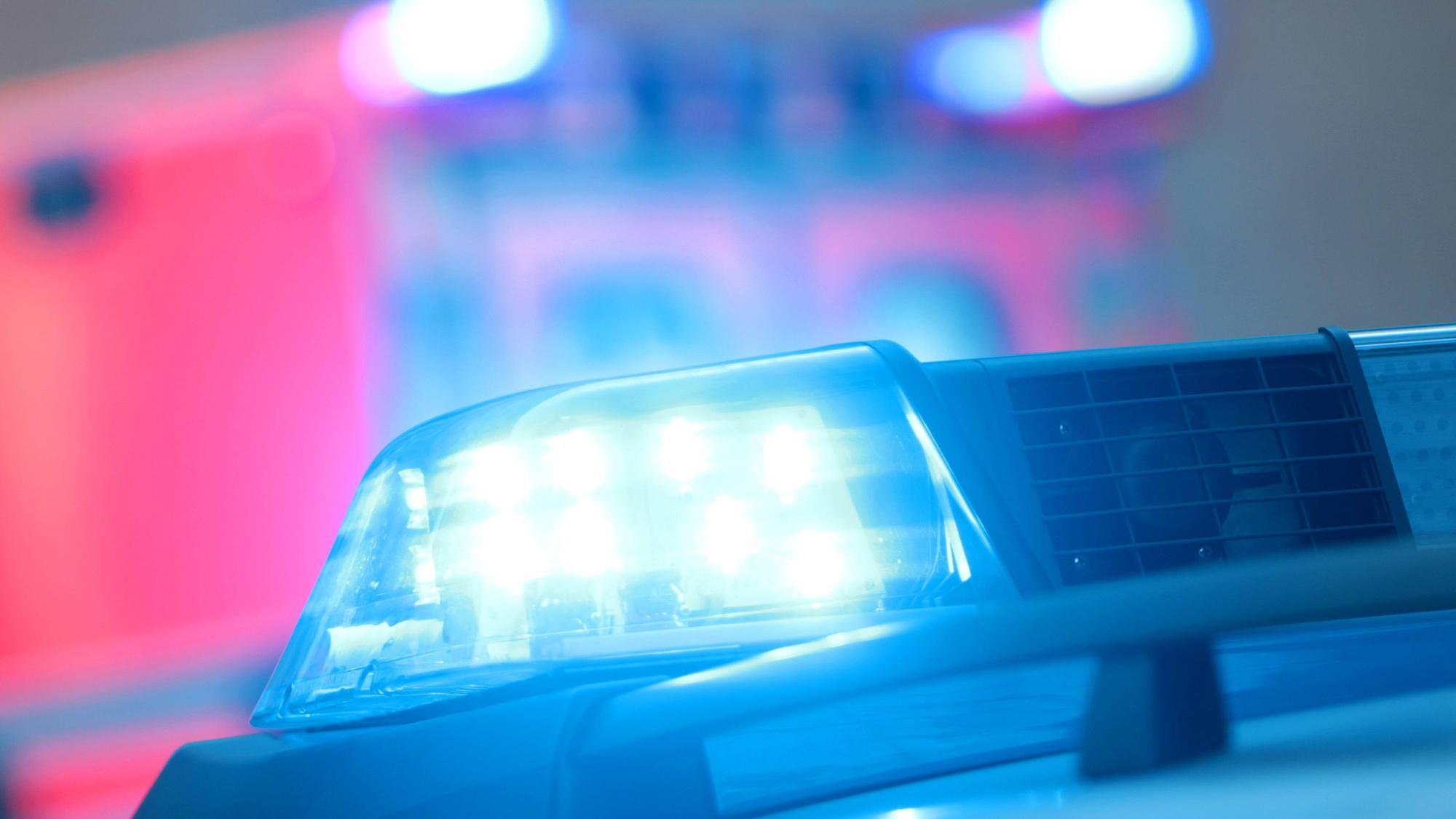 Ein Polizeiwagen mit eingeschaltetem Blaulicht und ein Rettungswagen bei einem Einsatz.