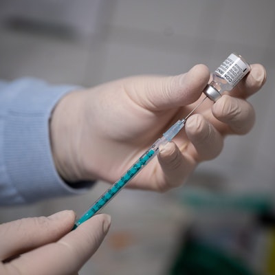 Ein Arzt zieht in einer Hausarztpraxis eine Spritze mit dem Corona-Impfstoff auf.