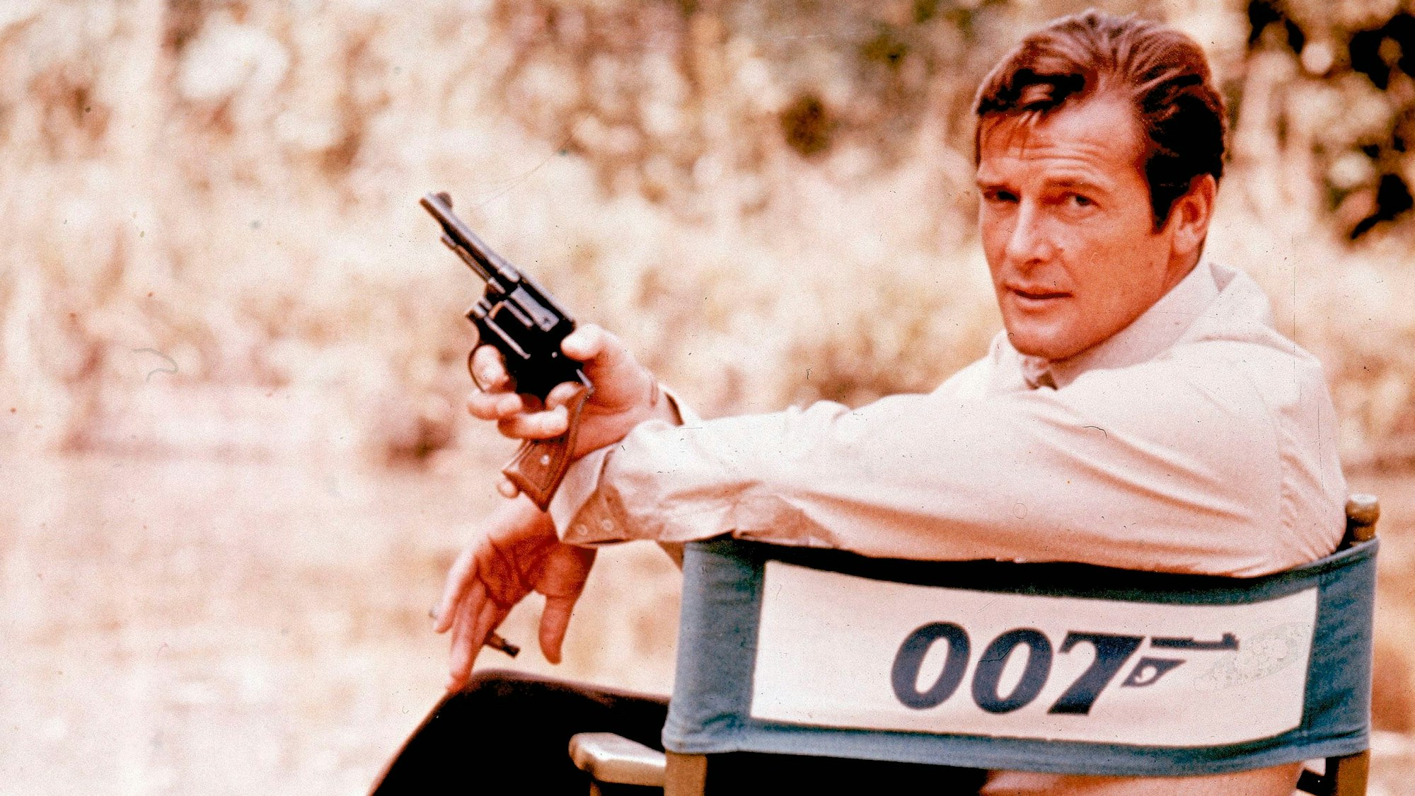 Der britische Schauspieler Roger Moore bei Dreharbeiten zum Film "James Bond 007 - Leben und sterben lassen" ("Live and Let Die") in einem Regiestuhl.