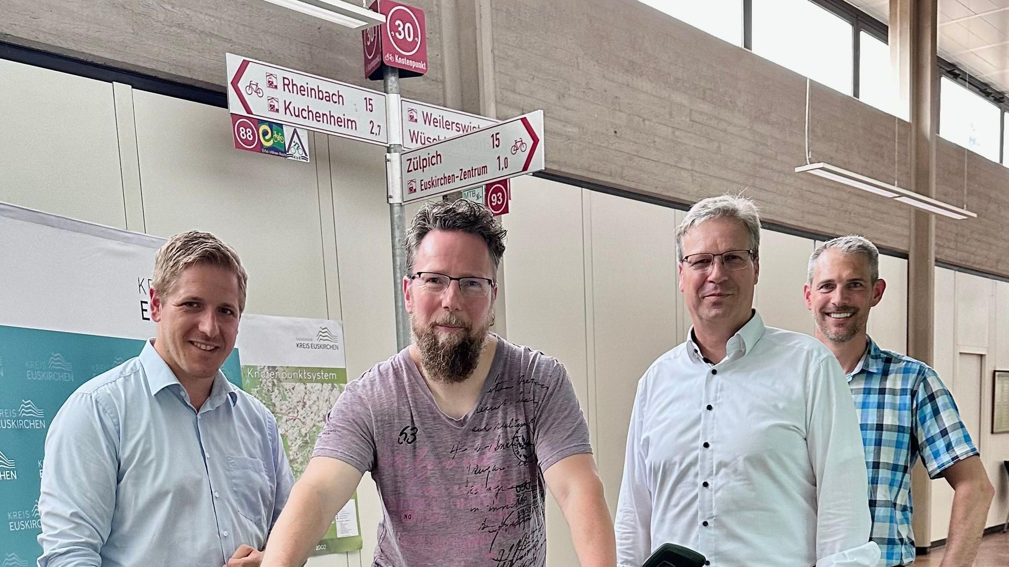 Fahrradbeauftragter Marcus Sprung sitzt auf einem Rad, daneben stehen Landrat Markus Ramers, Achim Blindert (Allgemeiner Verteter des Landrats) und Guido Schmitz, der zuständige Abteilungsleiter.