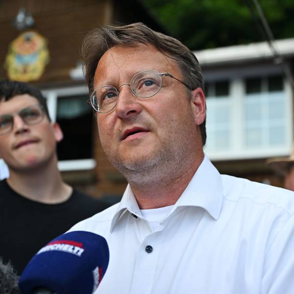 Robert Sesselmann trägt ein weißes Hemd. Er steht vor einem Mikrofon und gibt ein Interview.