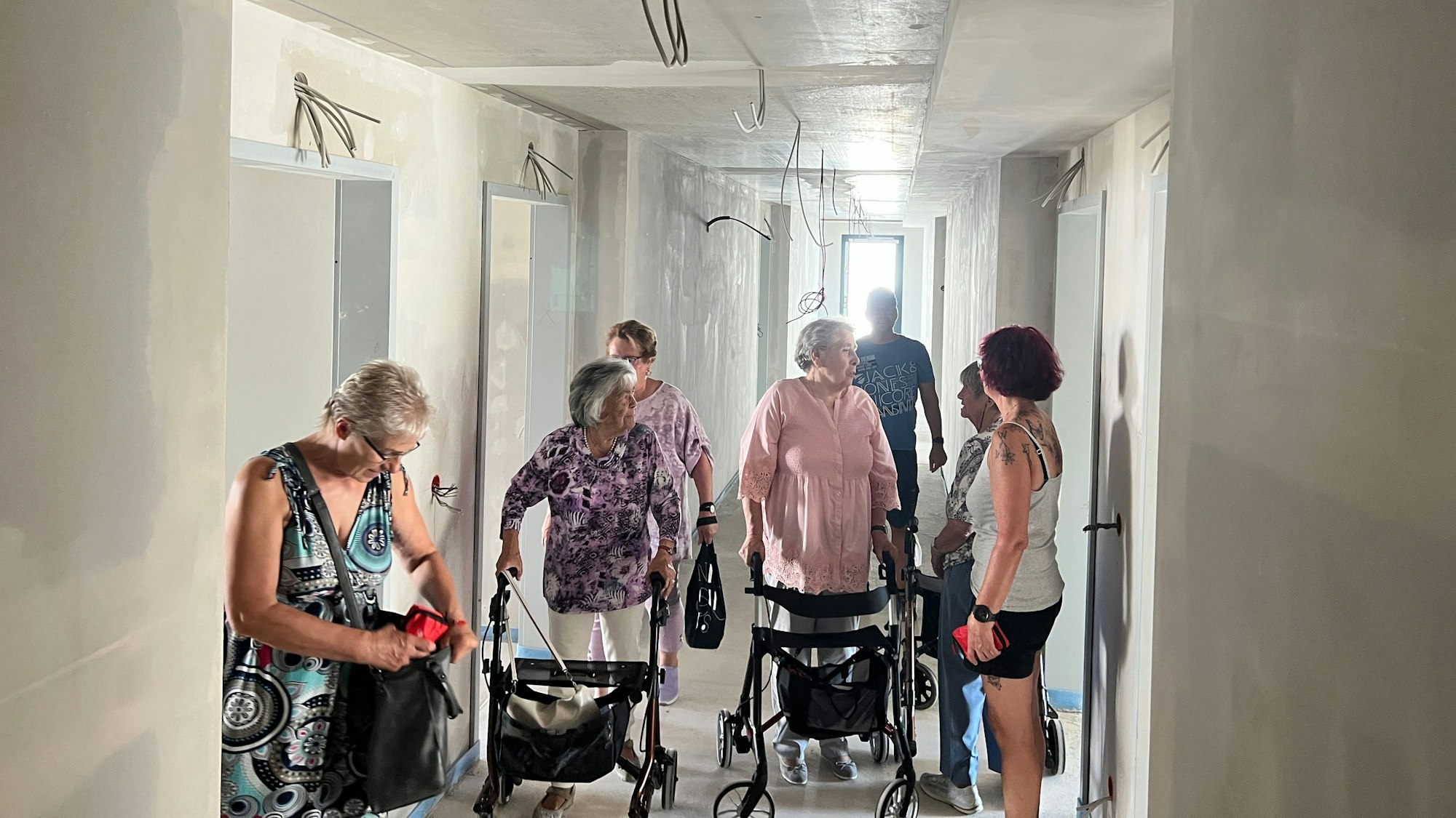 Seniorinnen mit Rollator besichtigen die Baustelle.