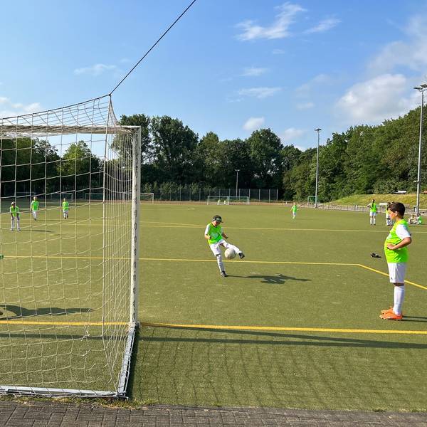 Jugendliche spielen Fußball auf einem Kunstrasenplatz.