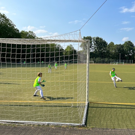 Jugendliche spielen Fußball auf einem Kunstrasenplatz.