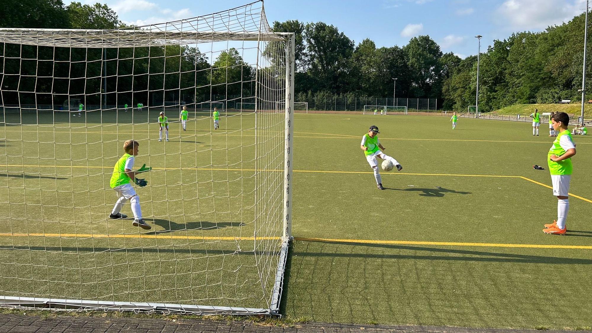 Jugendliche spielen Fußball auf einem Kunstrasenplatz.