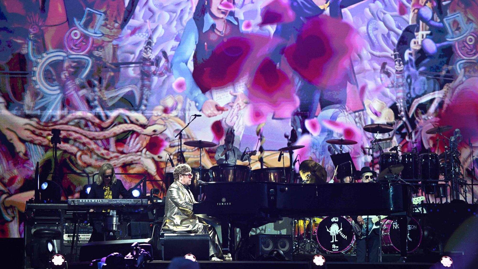 Elton John bei seiner Bühnenshow auf dem Glastonbury-Festival. Die Bühne ist bunt und farbenfroh.