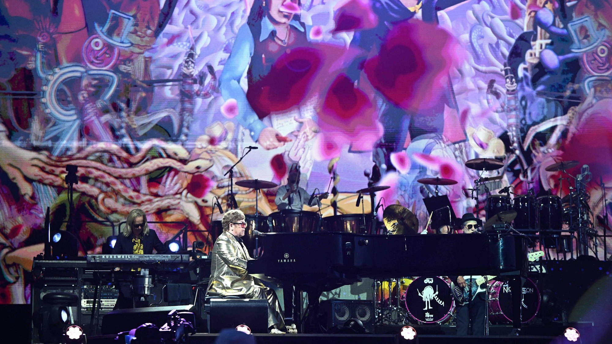 Elton John bei seiner Bühnenshow auf dem Glastonbury-Festival. Die Bühne ist bunt und farbenfroh.