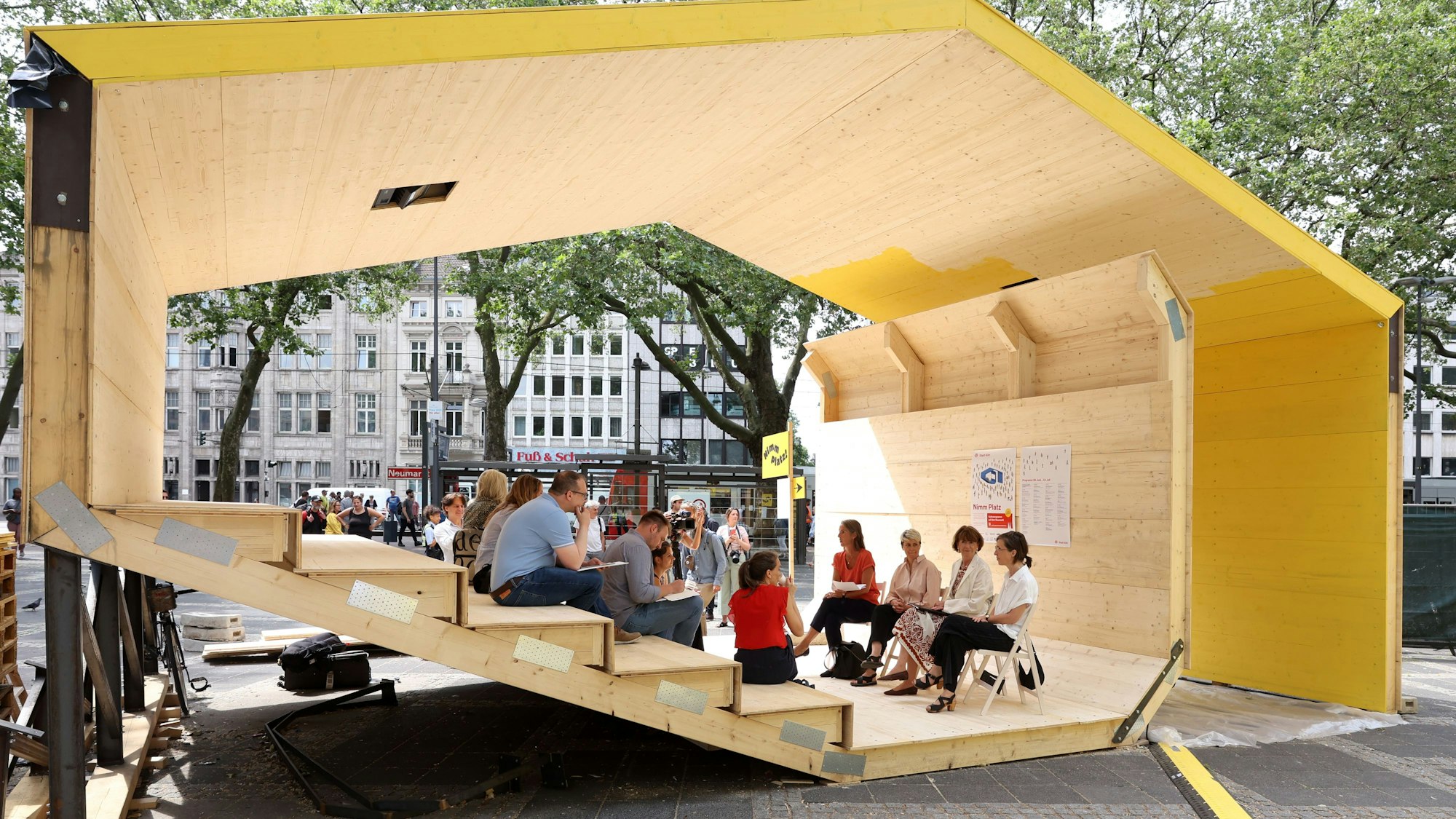 Ein gelber Holzpavillon auf einem Platz.