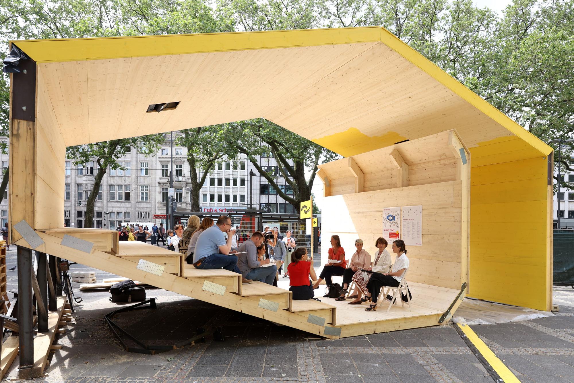 Menschen sitzen in einem Pavillon.