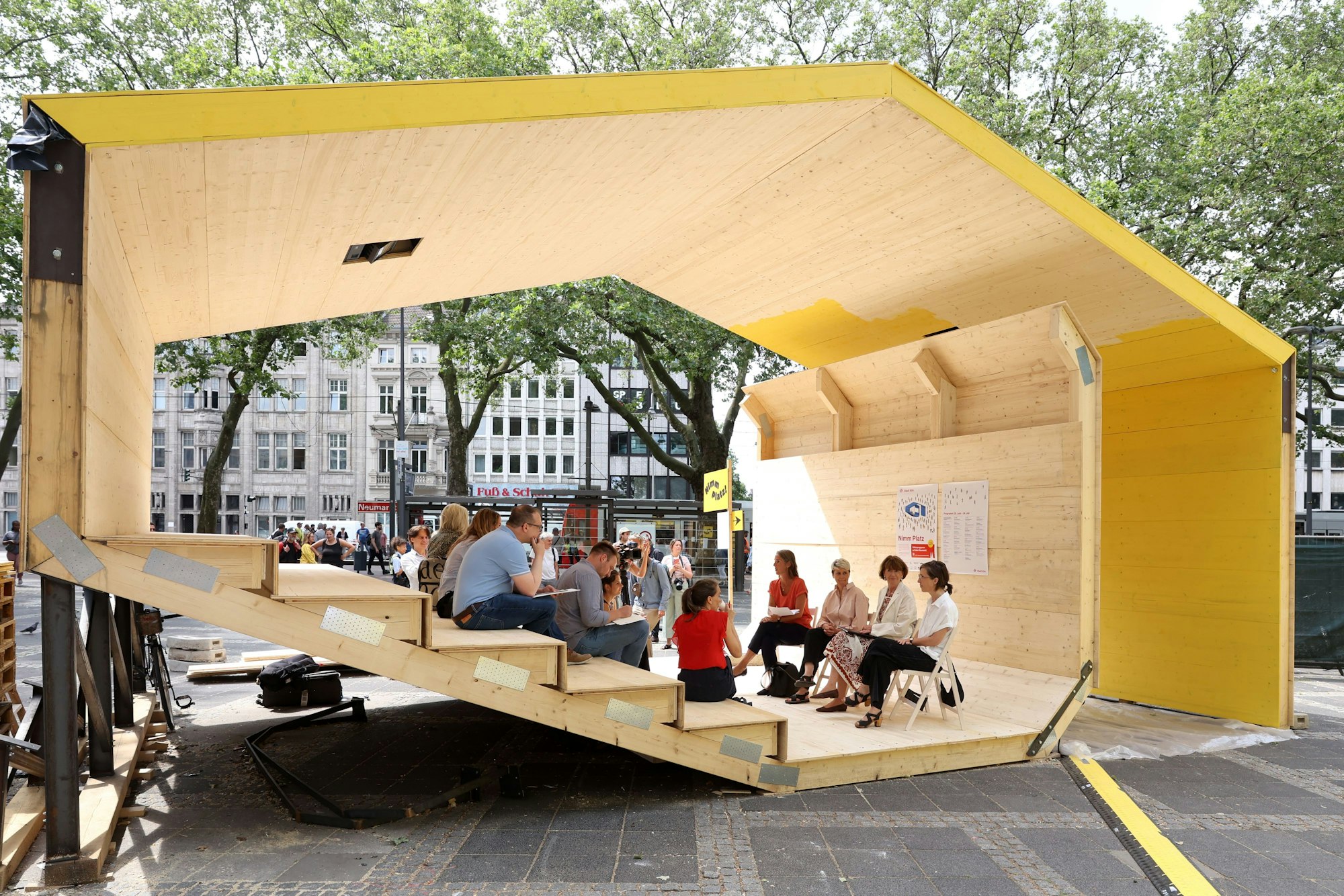 Menschen sitzen in einem Pavillon.