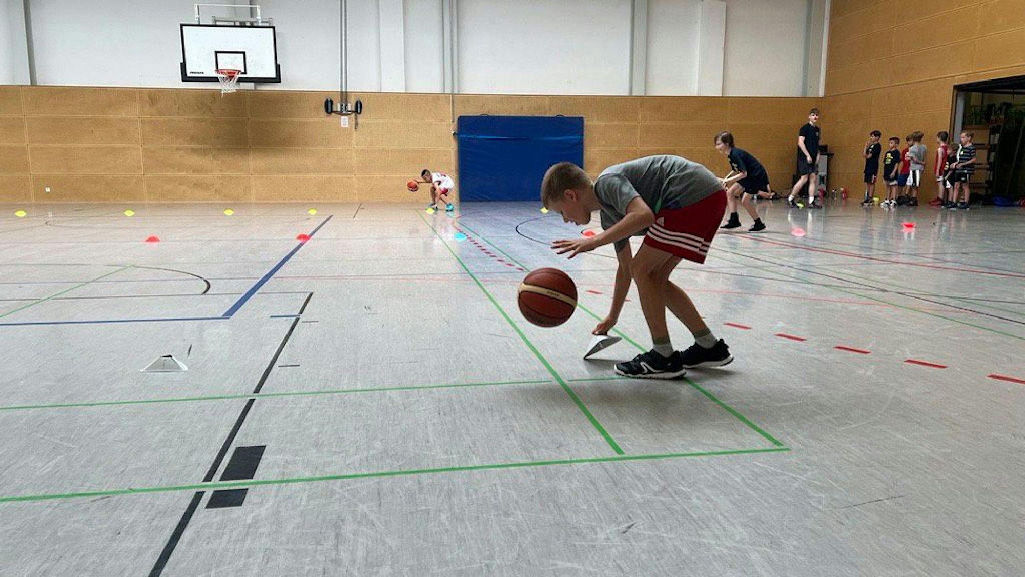 Bei dieser Übung soll mit einer Hand geprellt werden, während die andere das Slalomhütchen anhebt.