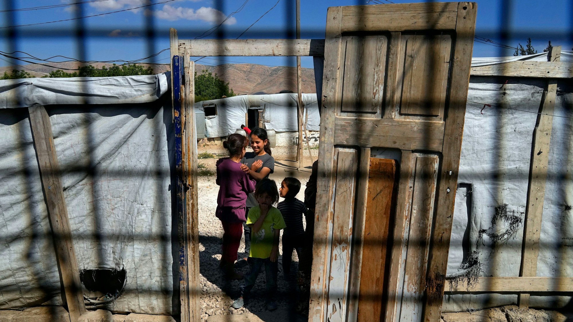Syrische Kinder, gesehen durch ein Zeltfenster, stehen in einem Flüchtlingslager