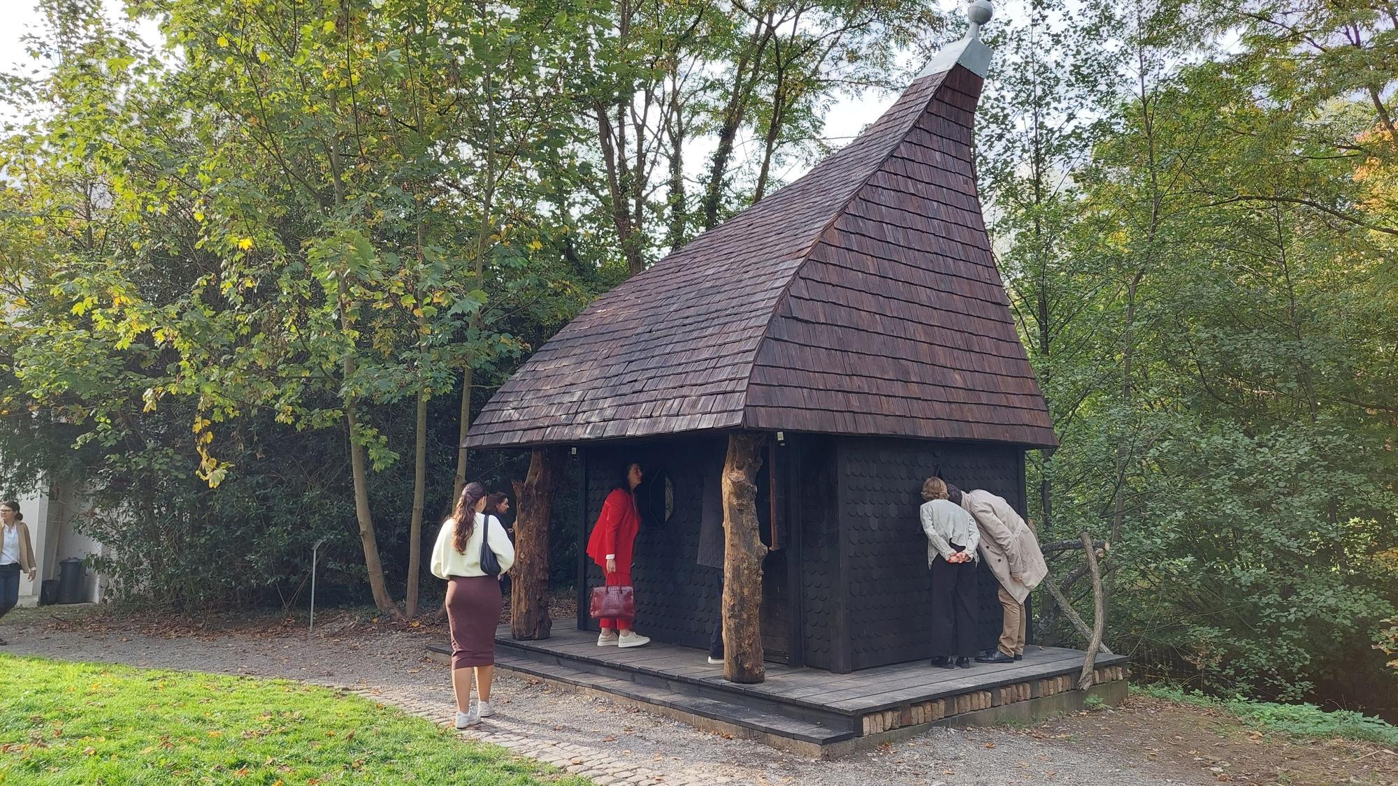 Menschen schauen in ein windschiefes Hexenhaus.
