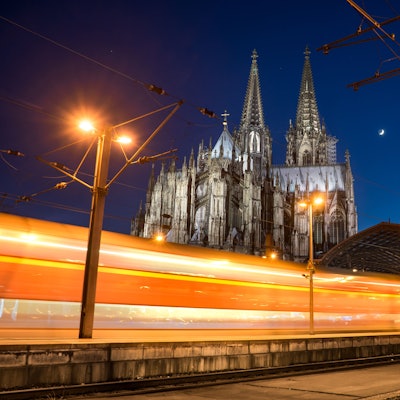 Ein Zug fährt im Dunkeln am Kölner Dom vorbei.