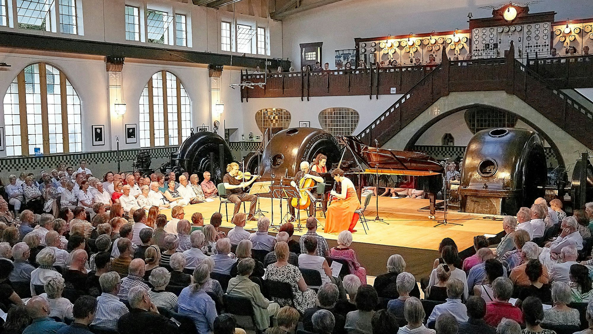 Blick in den ausverkauften Konzertsaal des Heimbacher Jugendstilkraftwerks. Hinter den Musikern auf der Bühne sind die großen Generatoren zu sehen.