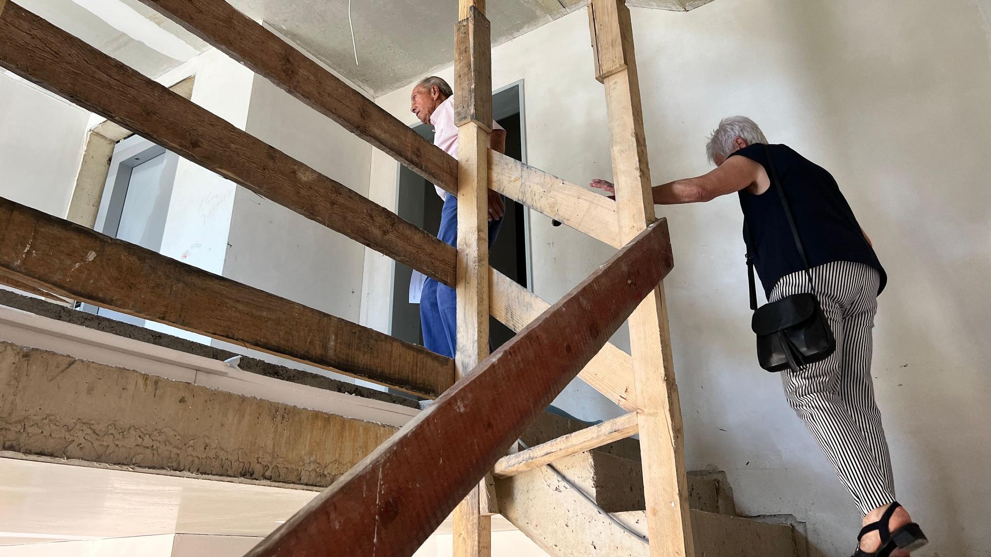 Zwei ältere Menschen gehen eine Holztreppe hoch.