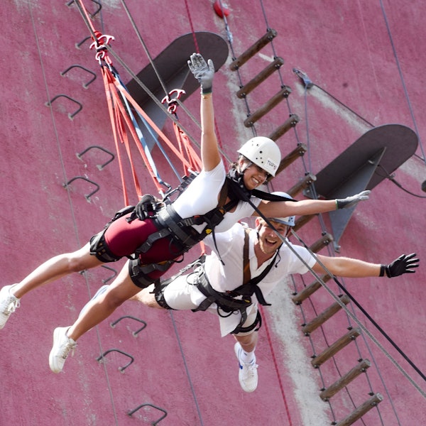 Das Foto zeigt einen Mann und eine Frau, die im Geschirr und an Seilen eine Wand herunterlaufen.