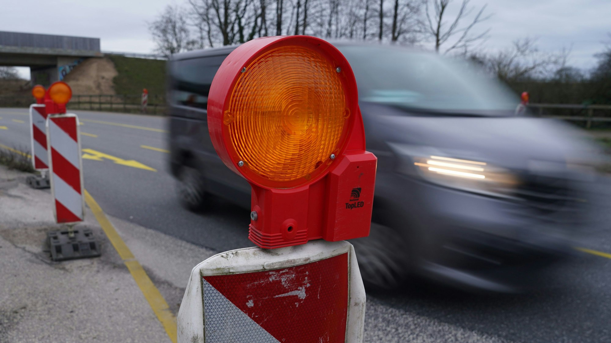 Ein Auto fährt auf einer Straßen-Baustelle an Warnbaken vorbei.
